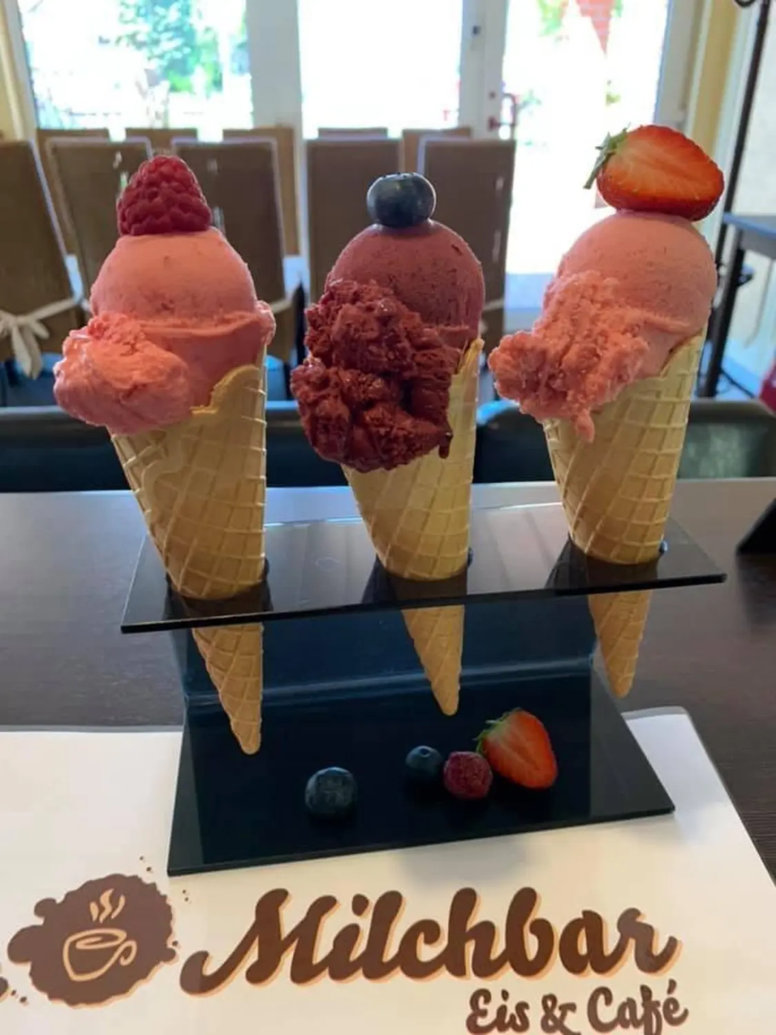 Drei Waffeltüten mit Fruchteis aus eigener Herstellung auf einem Milchbar-Platzset