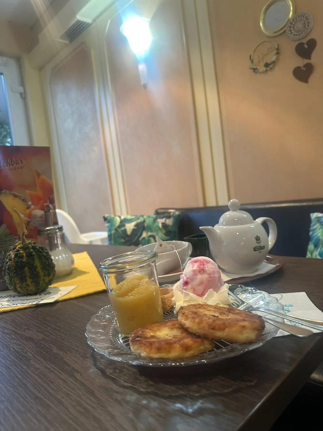 Apfelstrudel mit Sahne und Teekanne auf einem Cafétisch